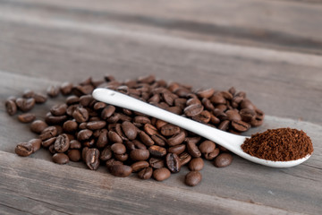  white ceramic spoon with ground coffee on a wooden background Fried Arabica grains 