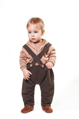 portrait of a charming one-year-old little boy on a white background, dressed in brown trousers, a beige hoodie,