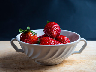 Strawberries in a cup on a table and black background