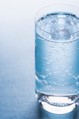 Glass of tonic water on blue background.
