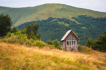 Fototapeta na wymiar A small wooden house in the mountains on the beautiful slope of Gimba Mountain in the Carpathians.