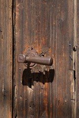 Large metal handle on an old wooden door, design of hardware and