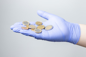 gloved hand offering a few euro coins. Concept of financial crisis after the coronavirus (covid19)