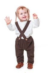 A cute stylish one year old boy in a white linen shirt and brown trousers looks a smile