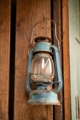 Blue retro old fashioned oil lamp hanging in a brown wooden background