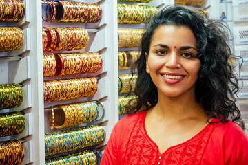 young indian woman show traditional ethnic bracelets in her small market in Goa