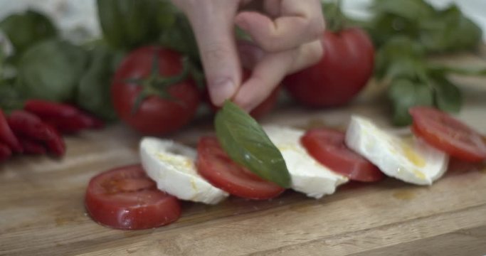 Preparare un'insalata caprese aggiungendo basilico fresco a pomodori e mozzarella di bufala