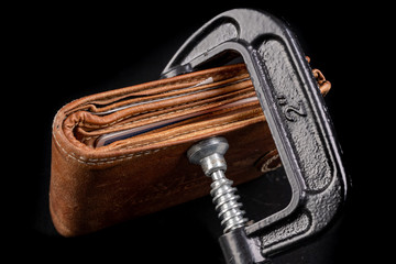 Personal wallet in a carpentry clamp. Personal finance in quarantine.
