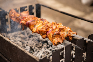 Cooking of a delicious shashlick (beef meat) and potatoes in an outdoor metal braizer with ashes and smoke 