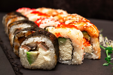 Sushi set nigiri and sushi rolls on a gray stone slate on a dark background