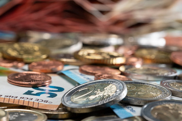 Money chaos, different Euro coins and bills. Closeup and 2 Euro coin in focus with other money out of focus