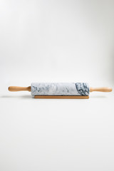 Rolling pin for dough made of gray marble with wooden handles and cradle. On a white isolated background.
