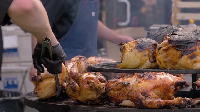 Super slow motion: chef grilling crispy whole chicken meat and cabbage on black brazier at summer local food market - close up view. Outdoor cooking, barbecue, gastronomy, cookery, street food concept