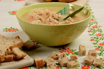 Vegetable soup with sausage and pieces of bread on a flower napkin