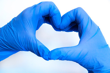 heart made of blue gloves on a white background. gloved hands.