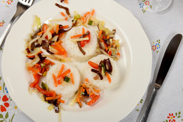 Vegetarian dish with white rice and vegetables on a white platethree piles of white rice with vegetables on a white plate as a side dish