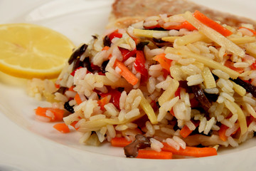 colorful rice with vegetables and fried fish on a white plate