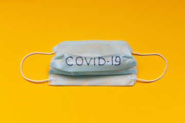 Medical mask with the inscription COVID-19. Coronavirus protection concept. One way to reduce the spread of the virus. Prevention of proliferation of COVID-19. Air pollution and virus protection.