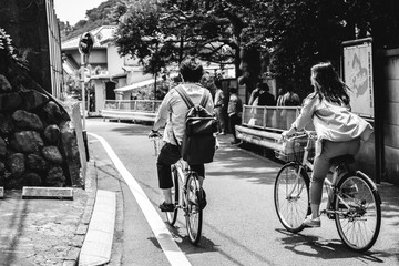 Couple in bikes from back at streets of Kamakura, Japan (in black and white)