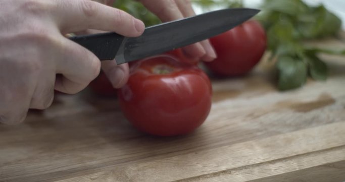 Tagliare un pomodoro su un tagliere per preparare una buona caprese con mozzarella di bufala