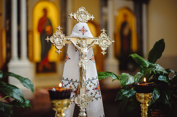 Gold cross with crucifix on a blurred background of icons, tied with an embroidered towel in the...
