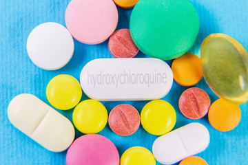 Background of colorful pills with hydroxychloroquine in center, health and medication, covid-19 treatment concept
