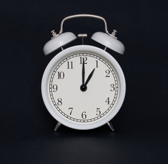 Old-style alarm clock, black and white, it's one o'clock.
