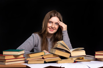 a young girl sits at a clutch holding her head with one hand. student with a smile prepares for the...