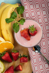A bowl of pudding with strawberry aroma with fruits on it, served with fresh mint leaves, orange and bananas
