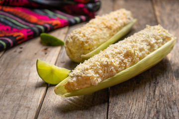 Mexican boiled corn on the cob with mayonnaise and cheese on wooden background