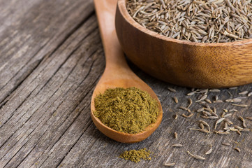 Pile of dry caraway spice with ground caraway powder in wooden spoon. Healthy food cumin spice...