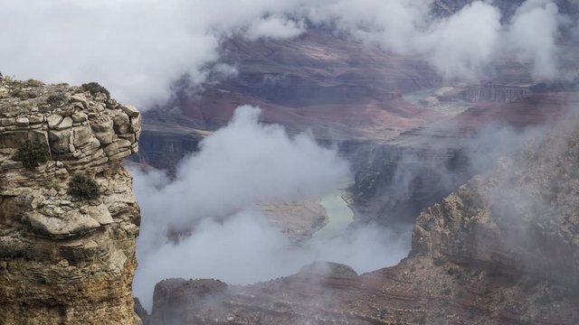 A long-lens timelapse looking down at the Colorado River flowing deep inside the Grand Canyon. Clouds start to cover the river before creeping up the canyon to completely obscure even foreground rock.