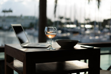 Laptop computer on a wooden table with a blurry marine background