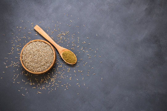 Pile of dry caraway spice with ground caraway powder in wooden spoon. Healthy food cumin spice concept ( Cuminum cyminum )