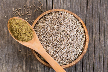 Pile of dry caraway spice with ground caraway powder in wooden spoon. Healthy food cumin spice...