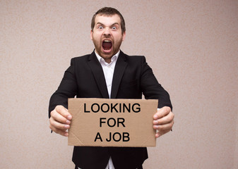 concept unemployment and coronavirus a man in black suit is holding a cardboard tablet with the...