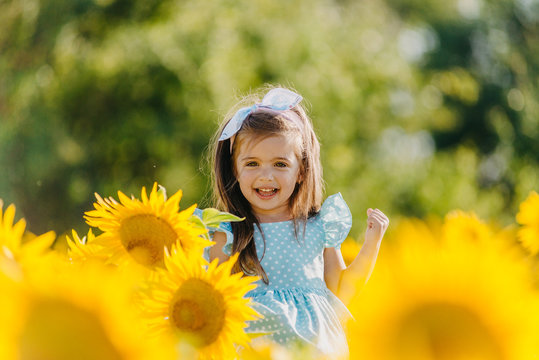 Little cheerful girl in a field of yellow sunflowers. Child and sunflower, summer, nature and fun. Summer rest