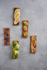 Healthy vegan sandwiches with hummus, guacamole, chocolate, cream, berries and raw spring vegetables on crispy rye bread. Flat lay on a gray background. Free empty space