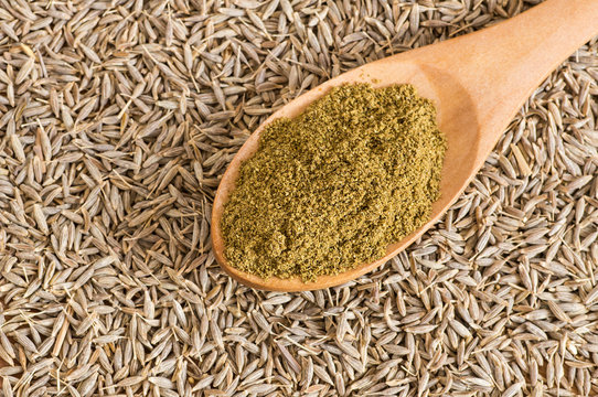 Pile of dry caraway spice with ground caraway powder in wooden spoon. Healthy food cumin spice concept ( Cuminum cyminum )