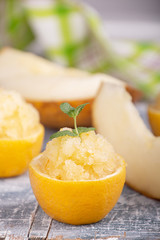 Melon and lemon fruit sorbet. Summer refreshing dessert in half of lemon fruit peel over on blue background.
