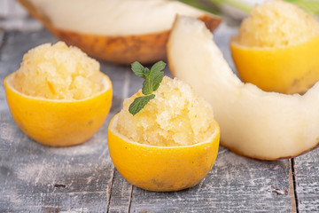 Melon and lemon fruit sorbet. Summer refreshing dessert in half of lemon fruit peel over on blue background.