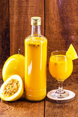 homemade and organic passion fruit juice, natural, made at home. Bottle of passion fruit juice on rustic wooden background.