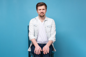 Thoughtful stressed young man on a chair sitting alone