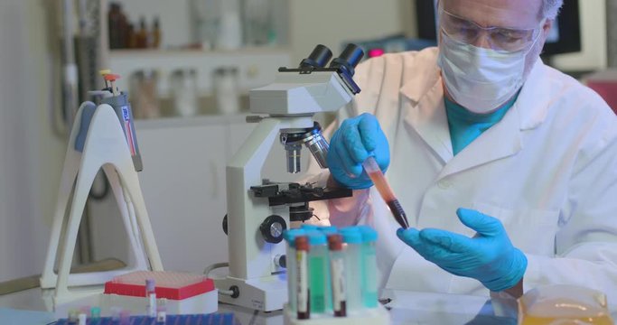 A medical researcher in a small laboratory holds a blood plasma sample he will use in trial tests for treating COVID19 patients.
