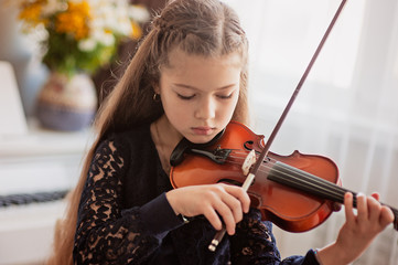Home lesson for a girl playing the violin. The idea of activities for children during quarantine....
