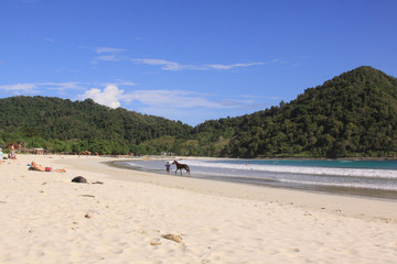 Man and horse on white sand beach, Mawun, Lombok