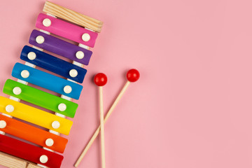Rainbow colored wooden toy xylophone isolated on pink background.
