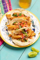 Mexican breaded fish tacos also called ensenada on turquoise background