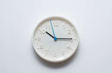 White wall clock hanging on a white wall