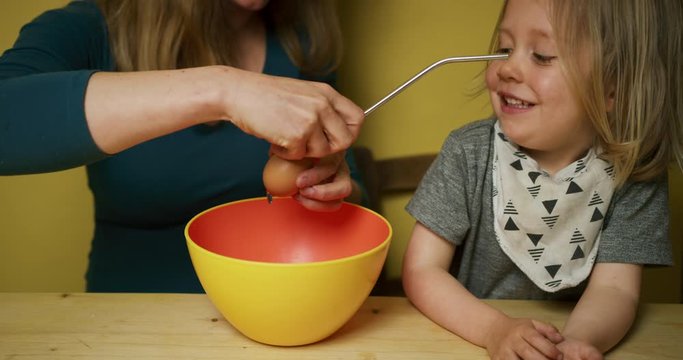 Preschooler blowing out eggs with his mother for Easter decorations
